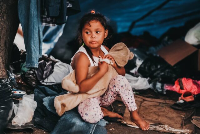 a little girl who survived Hurricane Eta sits on the street in Honduras